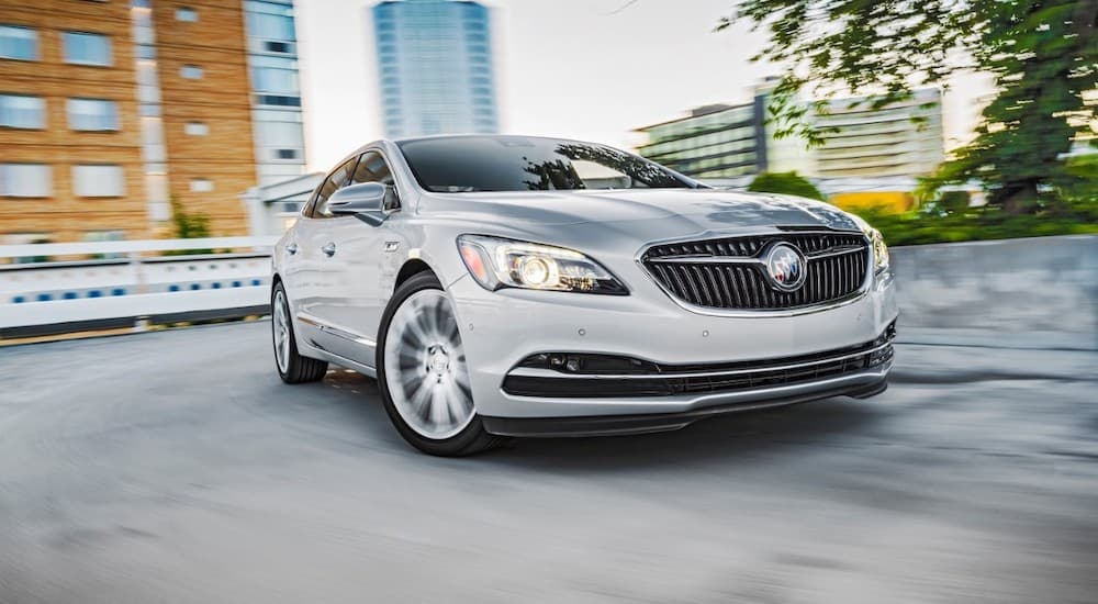 A silver 2017 Buick LaCrosse is shown driving on a winding city street.