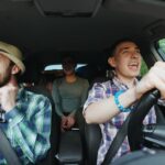 A group of friends are shown listening to music while driving a car.