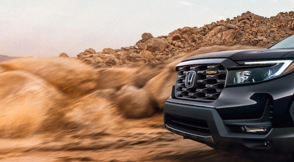 A close up of the front of a black 2022 Honda Passport Trailsport is shown after leaving a used Honda dealer.