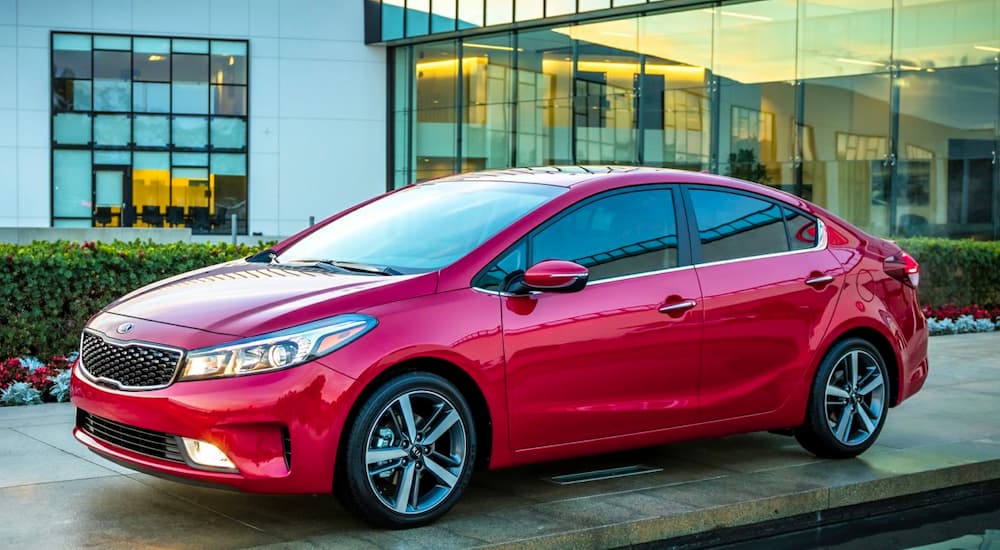 A red 2017 Kia Forte is shown parked outside of a used Kia dealership.