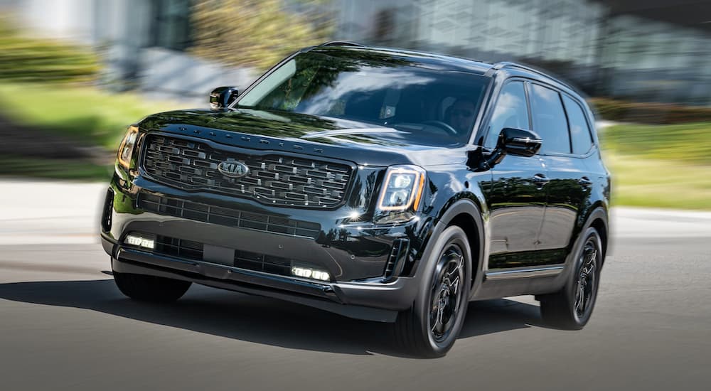 A black 2021 Kia Telluride is shown driving on an open road.