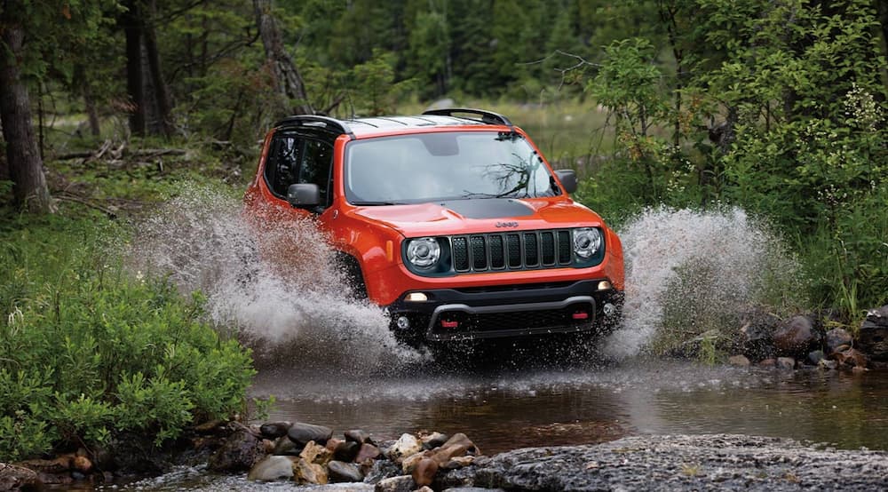 A red 2023 Jeep Renegade TraIlhawk is shown from the front while driving through a puddle during a 2023 Subaru Crosstrek vs 2023 Jeep Renegade comparison.
