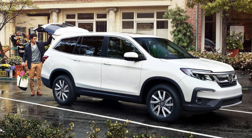 A white 2021 Honda Pilot is shown from the side with the lift gate open.