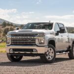 A silver 2023 Chevy Silverado 2500 HD is shown from the front at an angle during a 2023 Chevy Silverado 2500 HD vs 2023 Ford F-250 comparison.