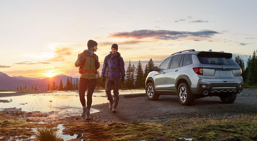 Two people are shown next to a 2023 Honda Passport Trailsport.