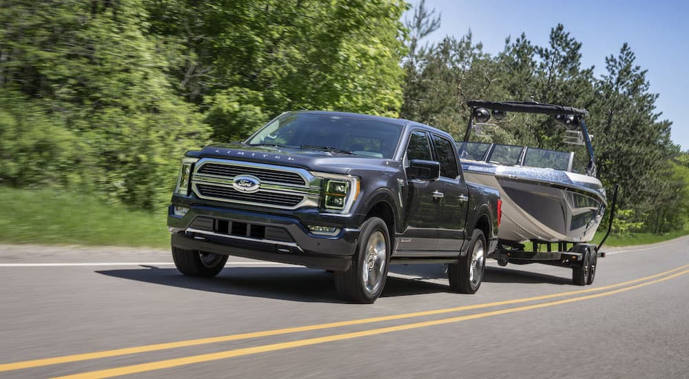 A grey 2022 Ford F-150 Platinum is shown from the front at an angle while towing a boat after leaving a Ford F-150 dealer.