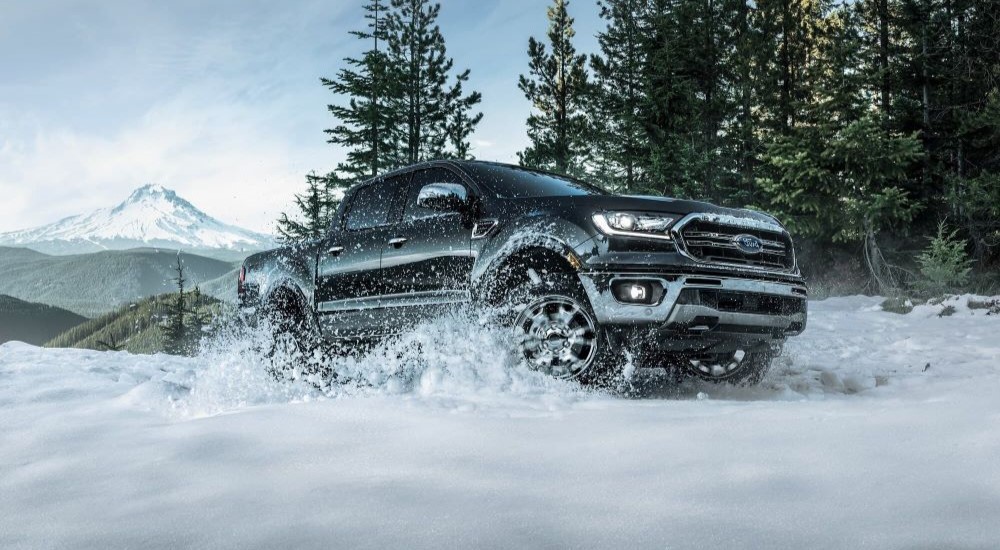 A black 2023 Ford Ranger is shown driving on the snow.
