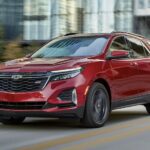 A red 2023 Chevy Equinox is shown driving down a highway after the owner checks out Chevy Equinox sales.