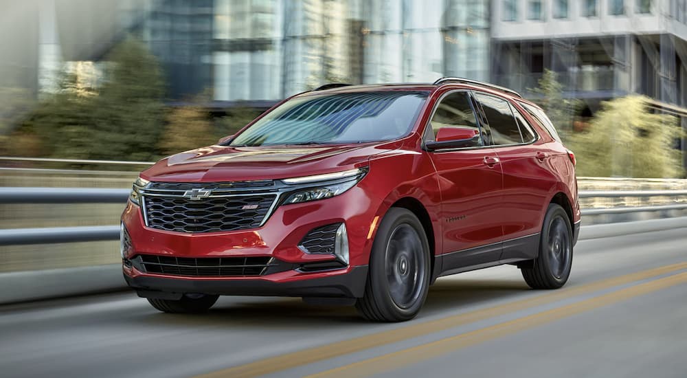 A red 2023 Chevy Equinox is shown driving down a highway after the owner checks out Chevy Equinox sales.