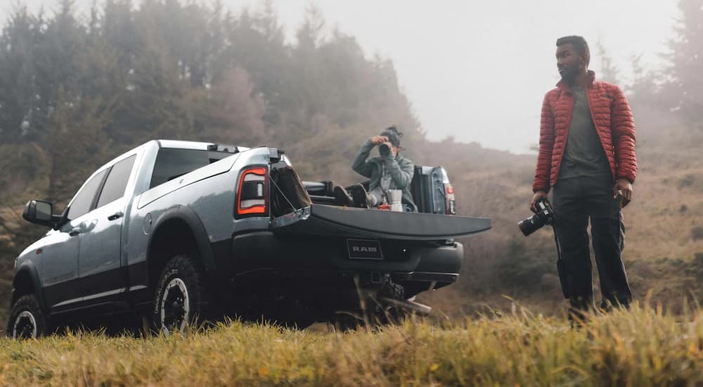 A man is shown walking near a silver 2023 Ram 2500 while someone sits in the bed.