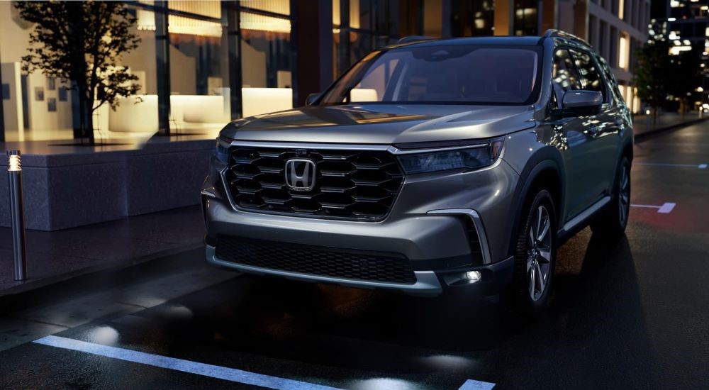 A silver 2023 Honda PIlot is shown parked on a city street.