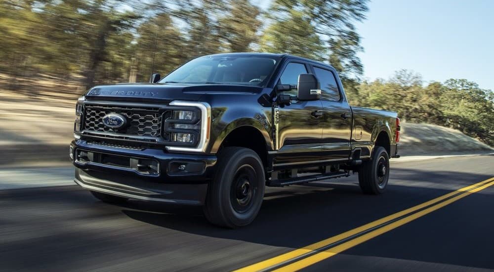 A black 2023 Ford F-250 is shown driving on a highway.