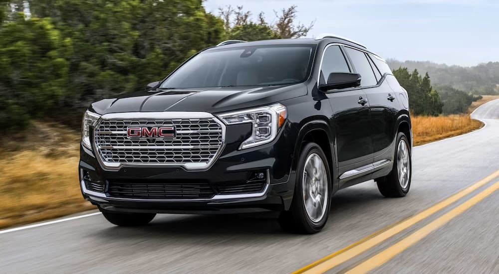 A black 2023 GMC Terrain Denali is shown cruising down a highway.