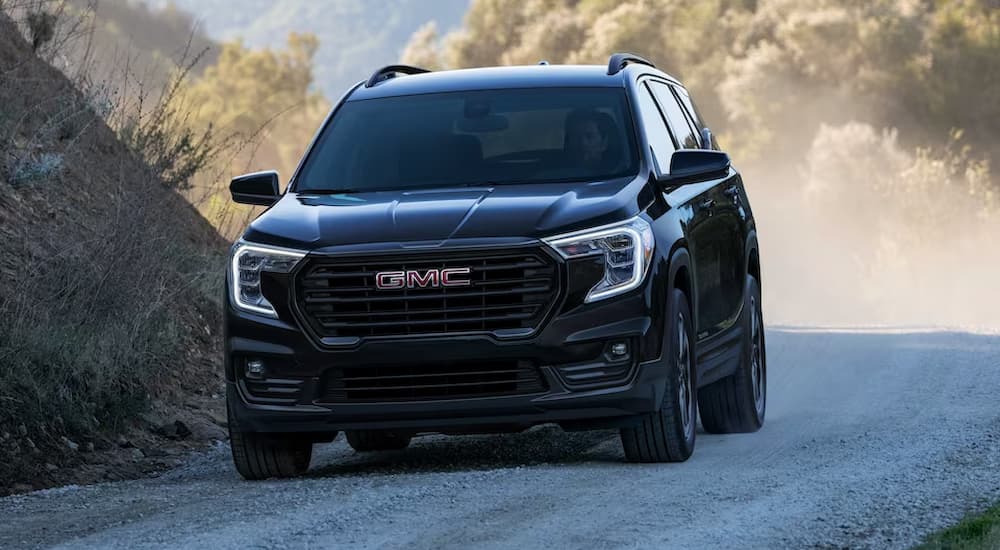 A black 2023 GMC Terrain is shown cruising down a gravel road in a 2023 GMC Terrain vs 2023 Toyota RAV4 comparison.