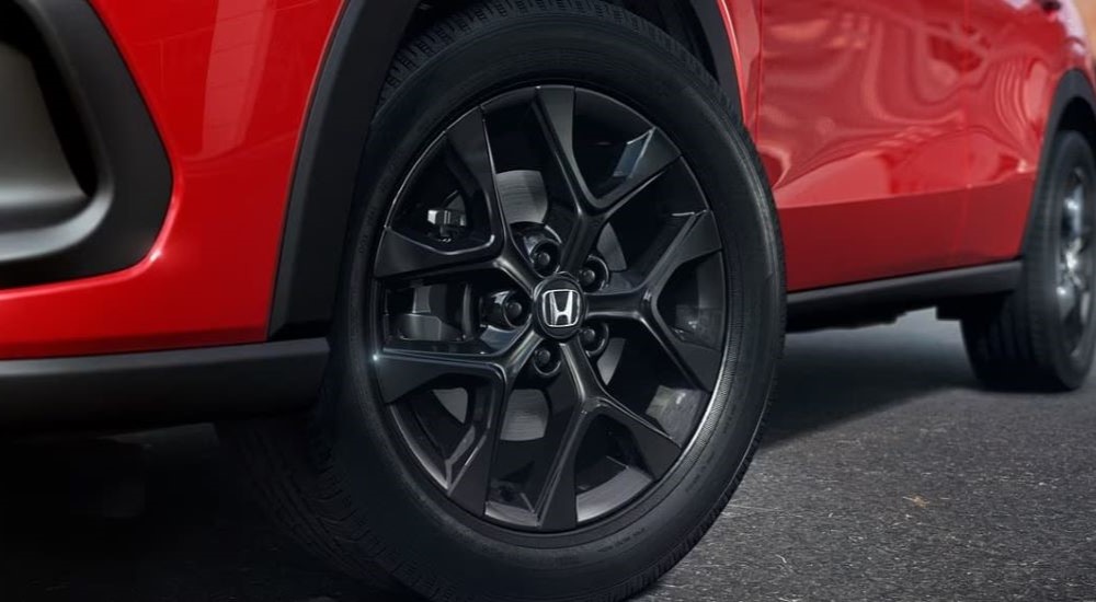A close up shows the black wheel on a red 2023 Honda HR-V Sport.