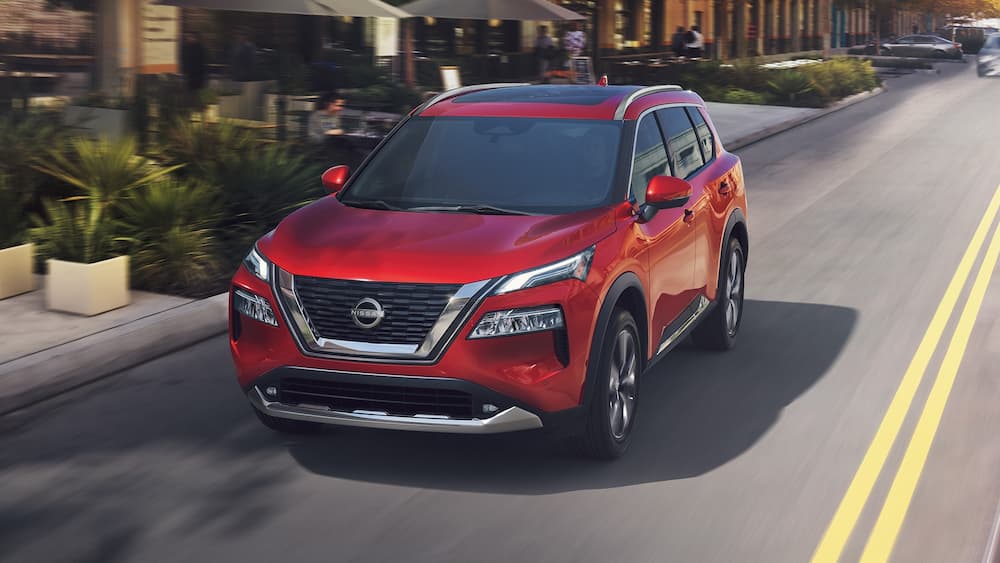 A red 2023 Nissan Rogue is shown driving on a road after winning a 2023 Nissan Rogue vs 2023 VW Tiguan comparison.