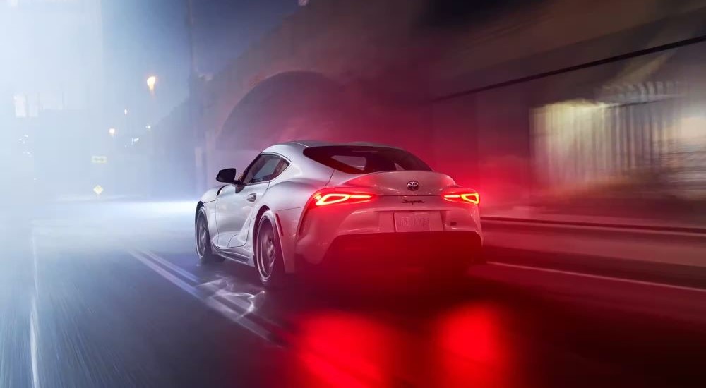 A white 2023 Toyota GR Supra is seen using its braking system on rainy road.