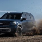 A 2023 dark blue Kia Telluride is off-roading on dirt.