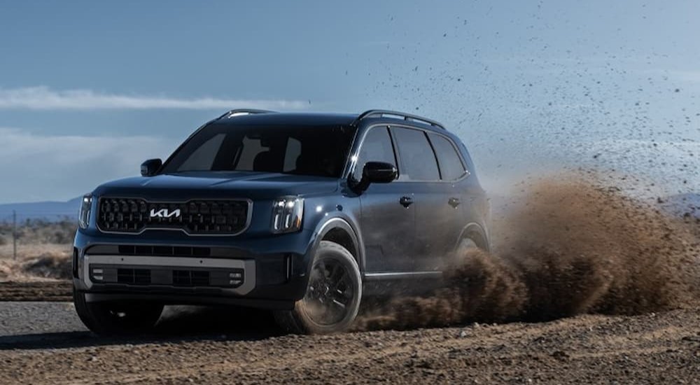 A 2023 dark blue Kia Telluride is off-roading on dirt.