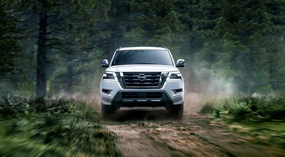 The front end of a white 2023 Nissan Armada is seen driving off-road.