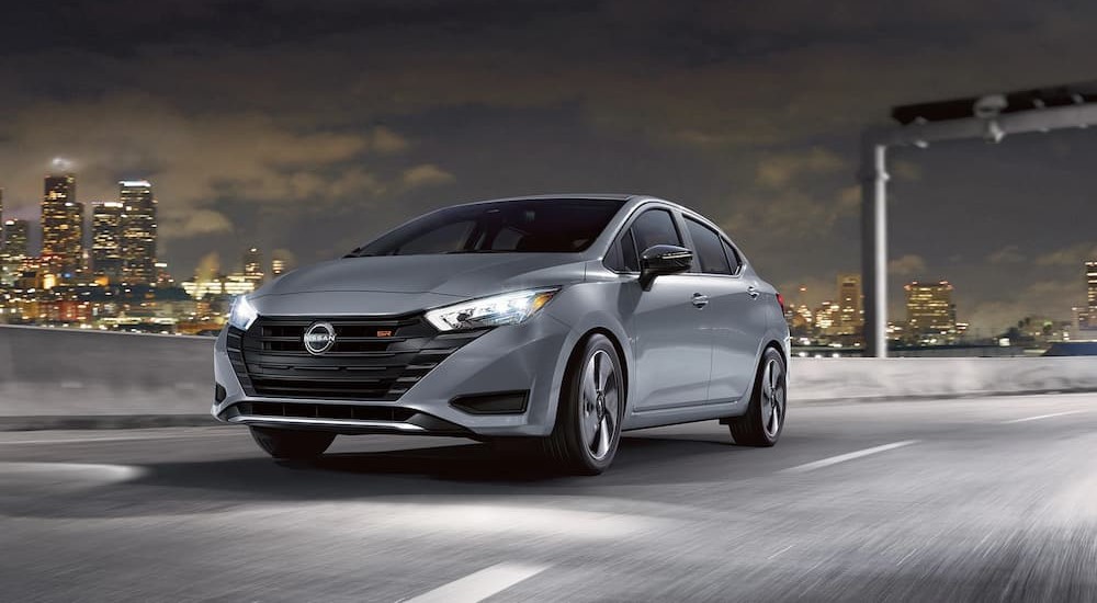 A silver 2023 Nissan Versa SR is seen driving down a highway.