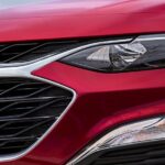 The grille of a red 2023 Chevy Malibu at a Chevy Malibu dealer is shown.