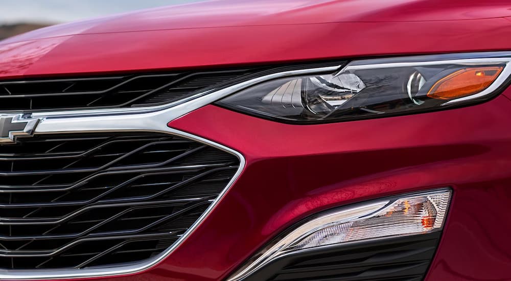 The grille of a red 2023 Chevy Malibu at a Chevy Malibu dealer is shown.