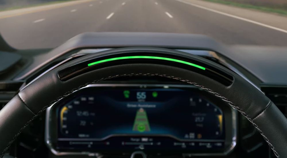 The top of the steering wheel of a 2022 Chevy Silverado is shown with a green light bar indicating the Super Cruise system is ready to be used. 