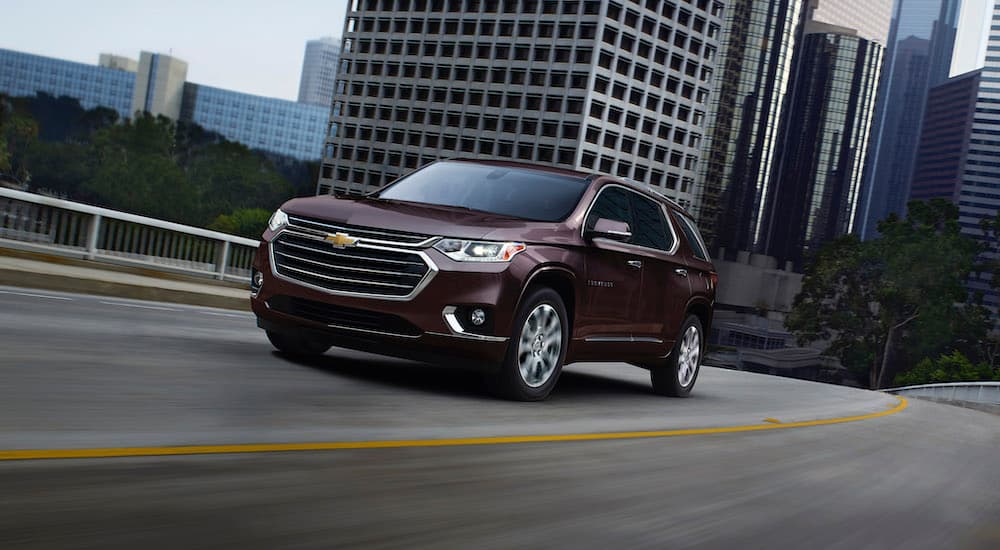 A maroon 2020 Chevy Traverse is shown driving through city streets.