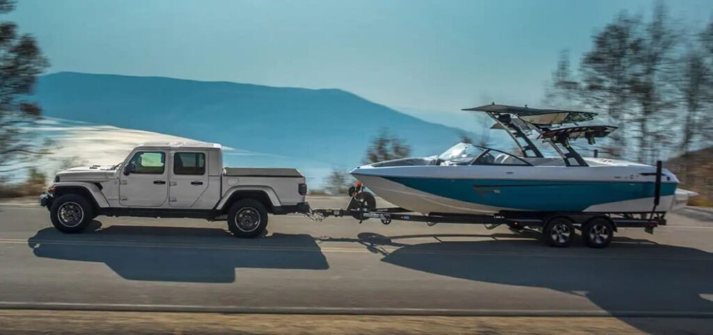 A silver 2023 Jeep Gladiator is shown towing a boat.