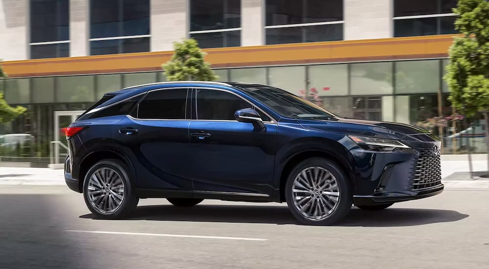 A blue 2023 Lexus RX is shown driving down a city street after leaving a Lexus dealer.