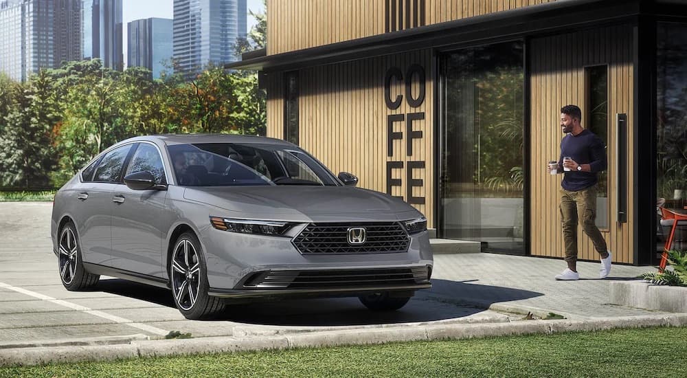 A grey 2023 Honda Accord is shown from the front at an angle at a coffee shop.