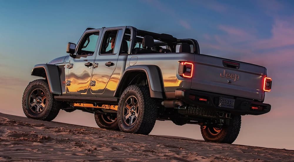 A silver 2023 Jeep Gladiator is shown from the rear at an angle after leaving a dealer that has a Jeep Gladiator for sale..
