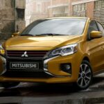 A yellow 2023 Mitsubishi Mirage for sale is shown parked on a street.