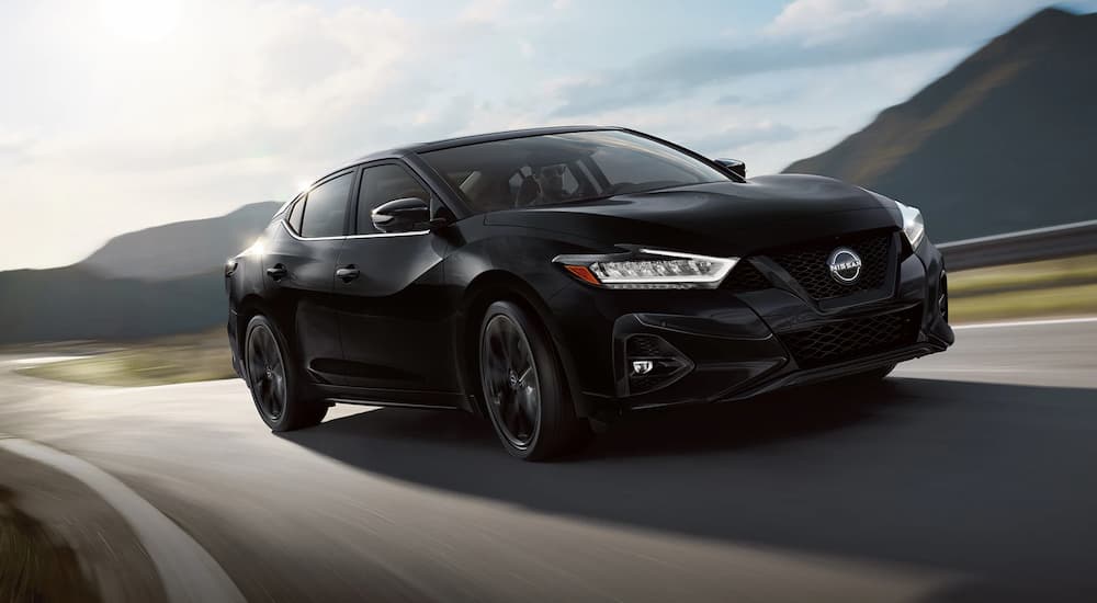 A black 2023 Nissan Maxima SR is shown driving down the highway.