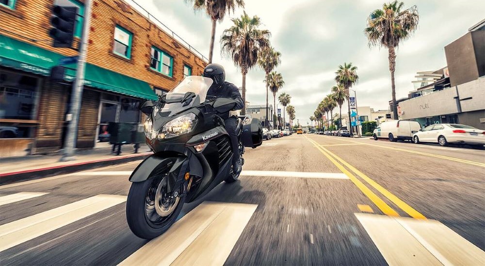 A black 2023 Kawasaki Concours 14 ABS is shown driving down a city street.