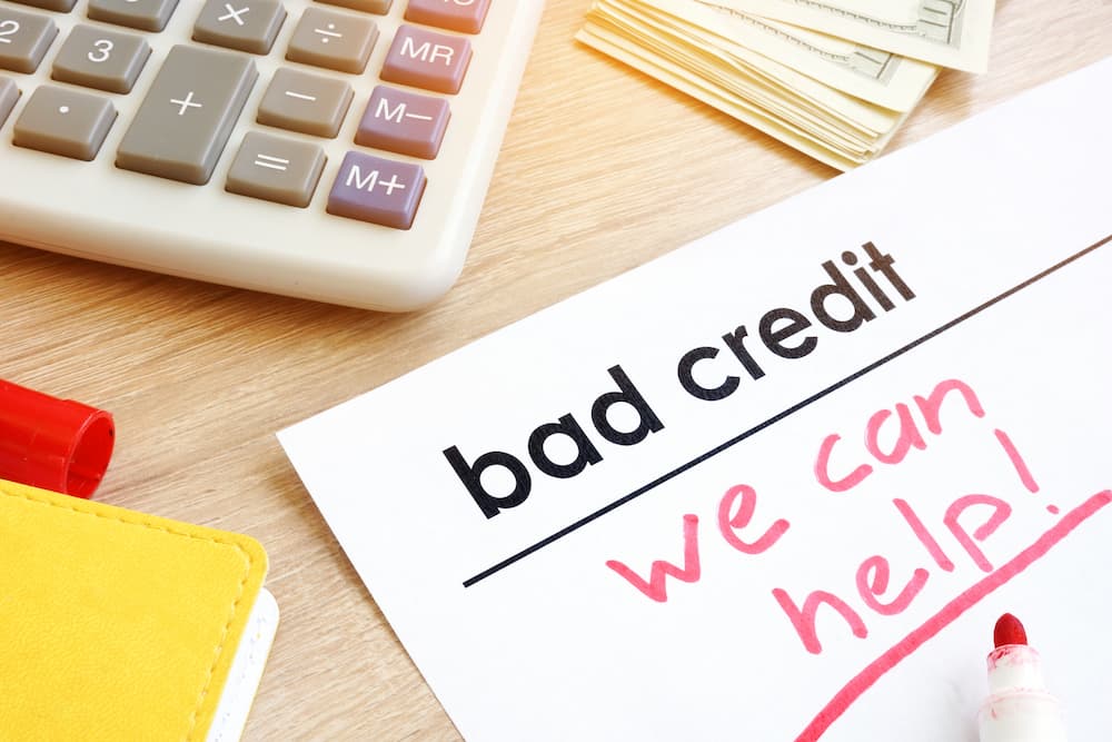 Bad credit we can help' is shown written on a piece of paper.