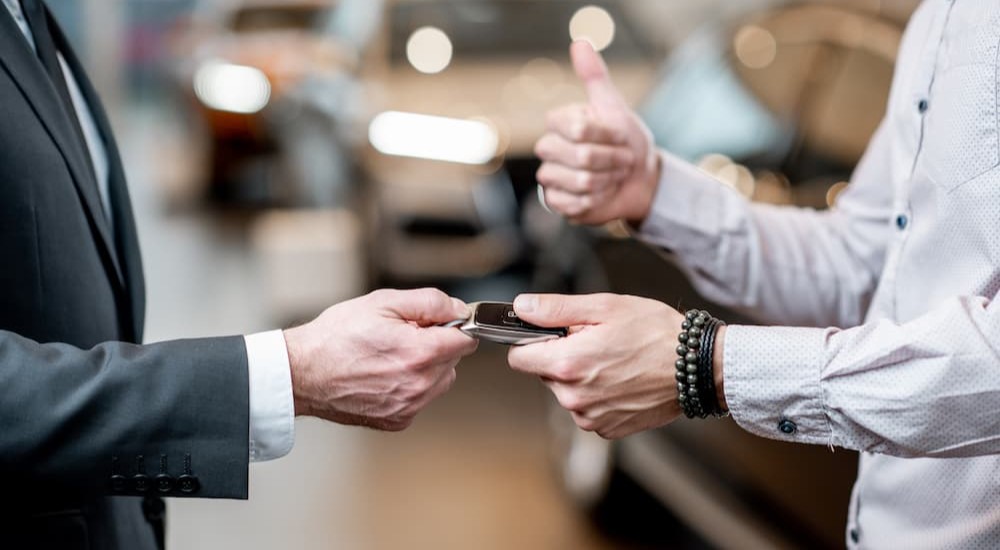 A salesman is seen handing car keys over to his customer.