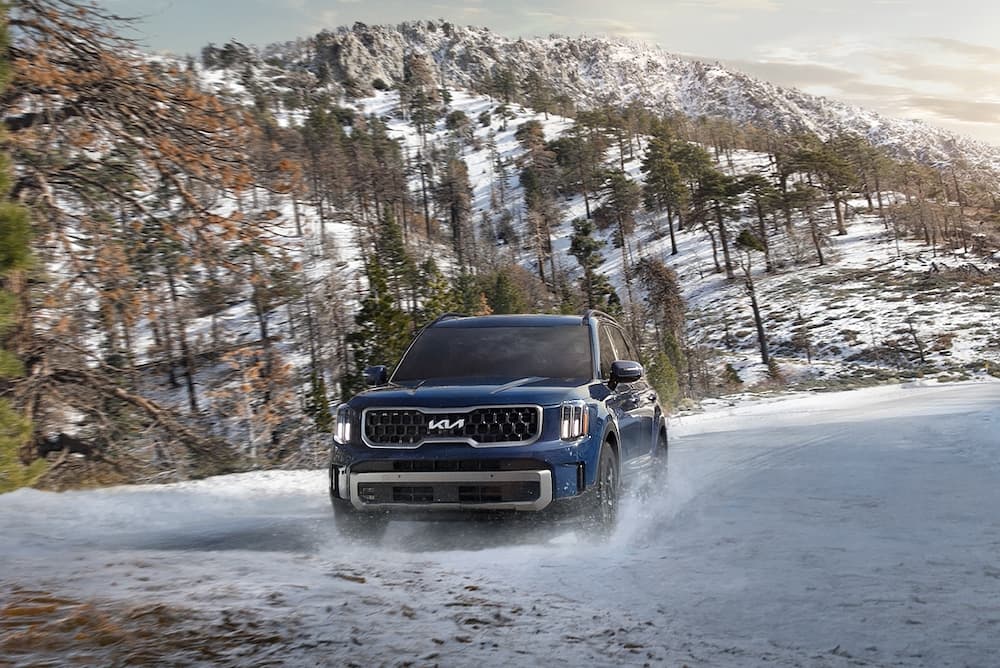 A blue 2023 Kia Telluride for sale is seen off-roading on snow.