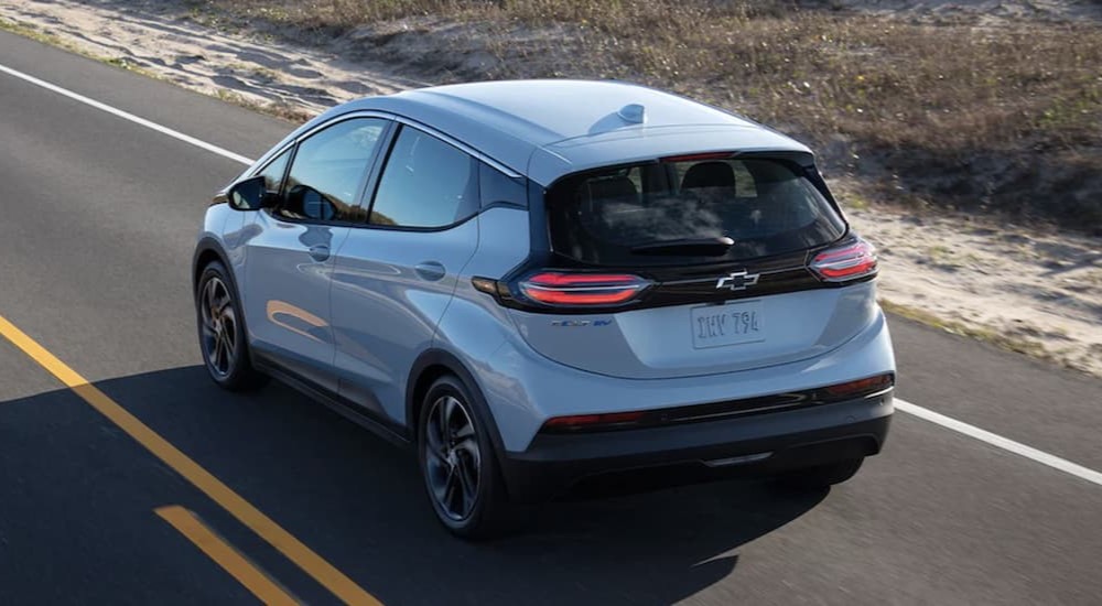A white 2023 Chevy Bolt EV is shown driving on a highway.