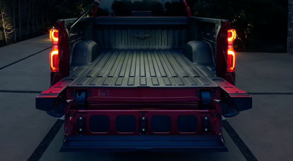 A red 2023 Silverado 1500 tailgate is shown at night with the MultiFlex Tailgate in the step position.
