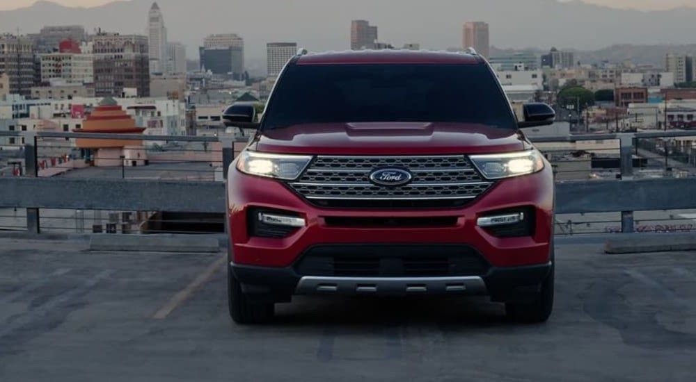 A red 2023 Ford Explorer is shown parked near a city.