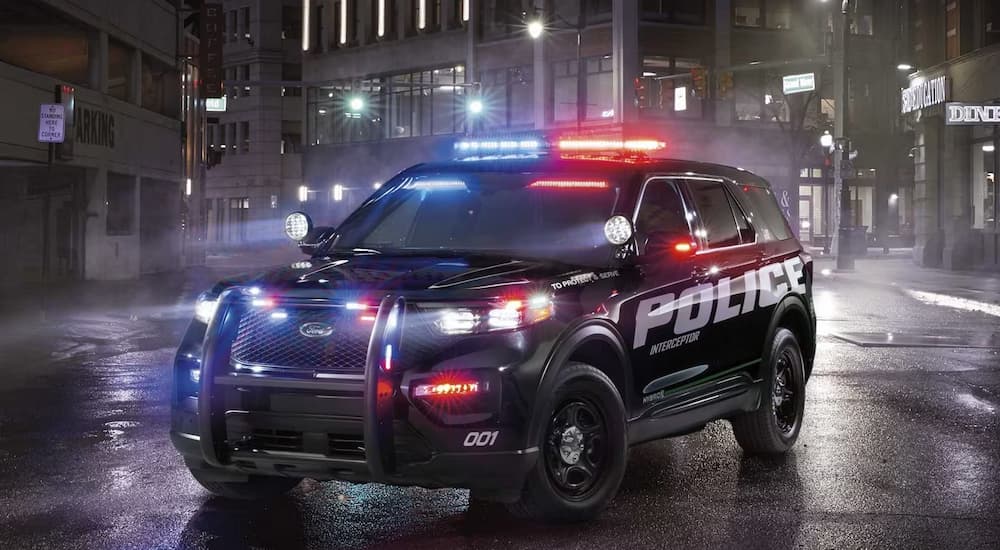 A 2023 Ford Explorer Police Interceptor Utility, a variant of the normal Ford Explorer for sale, is shown with its emergency lights on in a city.