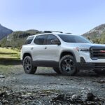 A white 2023 GMC Acadia is shown parked off road after competing in a 2023 GMC Acadia vs 2023 Kia Sorento comparison.