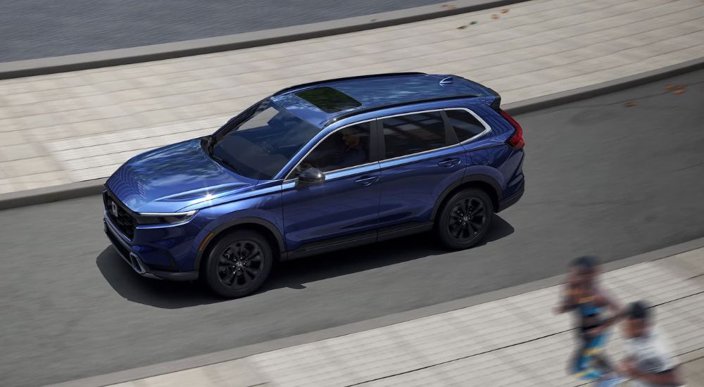 A blue Honda CR-V driving shows the difference between the 2023 Honda CR-V vs 2023 Mazda CX-5.