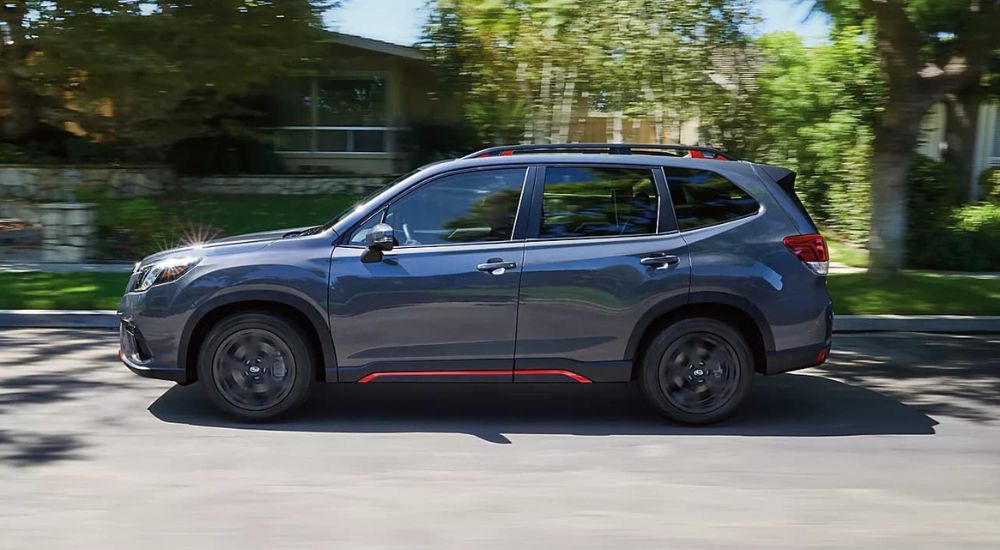 The 2023 Subaru Forester is shown from the side driving down a suburban street.