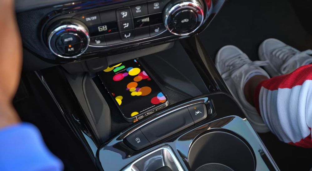 A smartphone is shown charging on the wireless charging pad of the 2024 Chevy Trax.