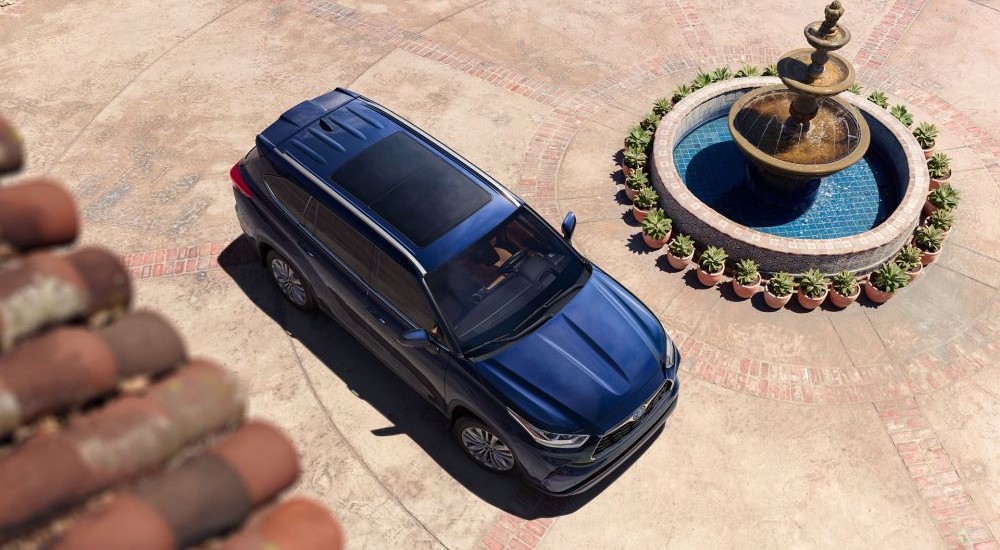 The aerial view of a blue 2023 Toyota Highlander Platinum is shown parked near a fountain.