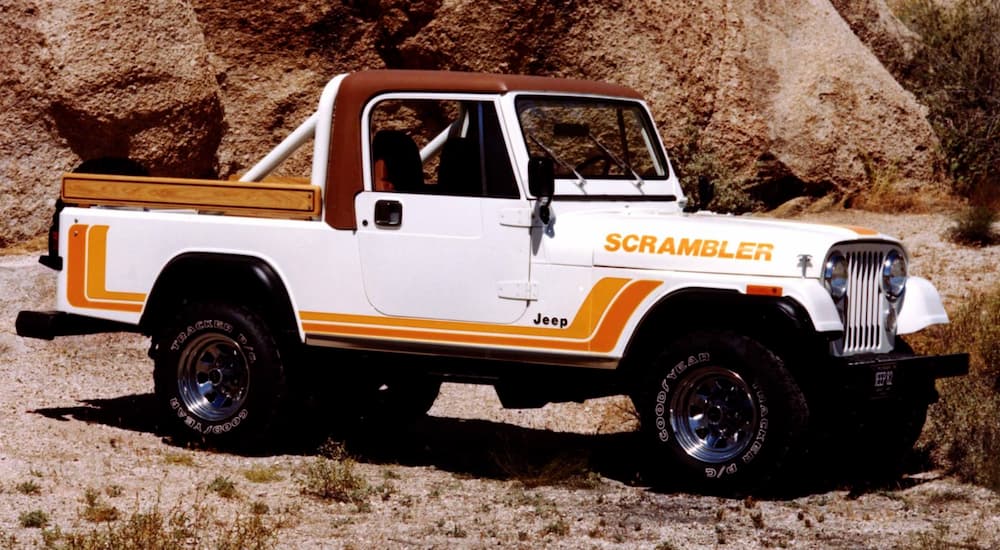 A white and orange 1982 Jeep CJ-8 Scrambler is shown parked off-road.