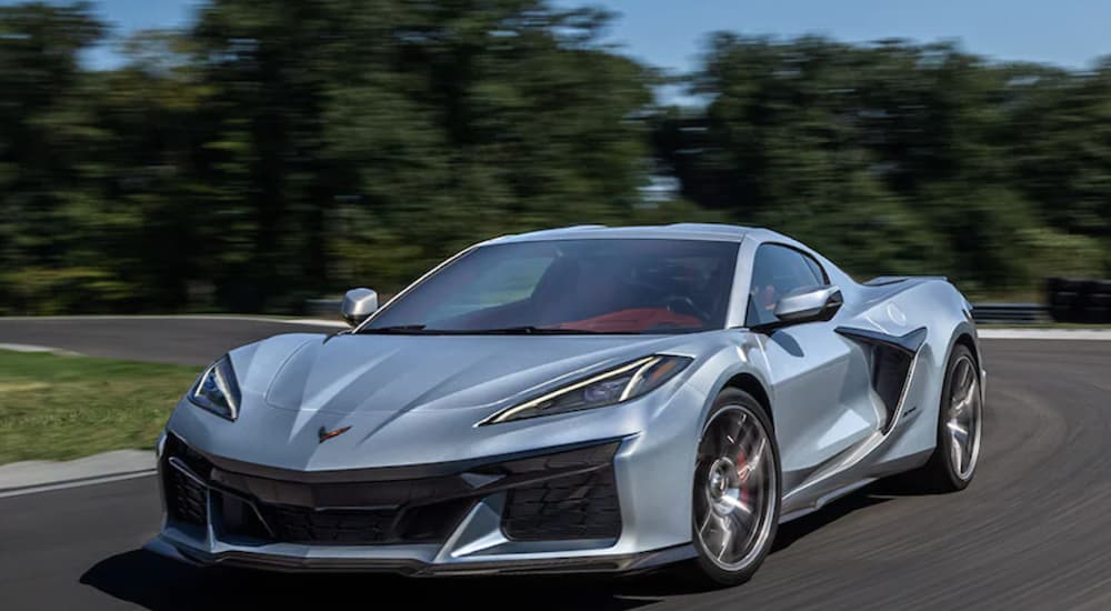 A silver 2023 Chevy Corvette Z06 is shown driving on a track after visiting a Chevrolet dealer.